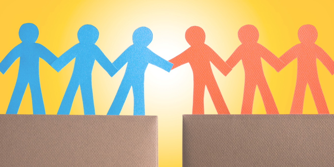 Blue paper people reaching across a gap to hold hands with red paper people